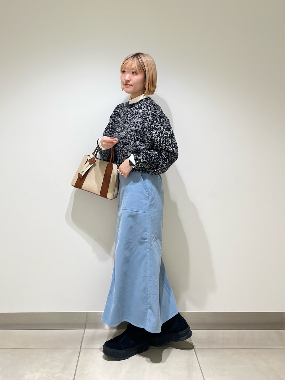 ホワイト系のTシャツ/カットソー、ブラック系のニット/セーター、ブルー系のスカートを着用したレディースの冬コーディネートの2枚目の写真