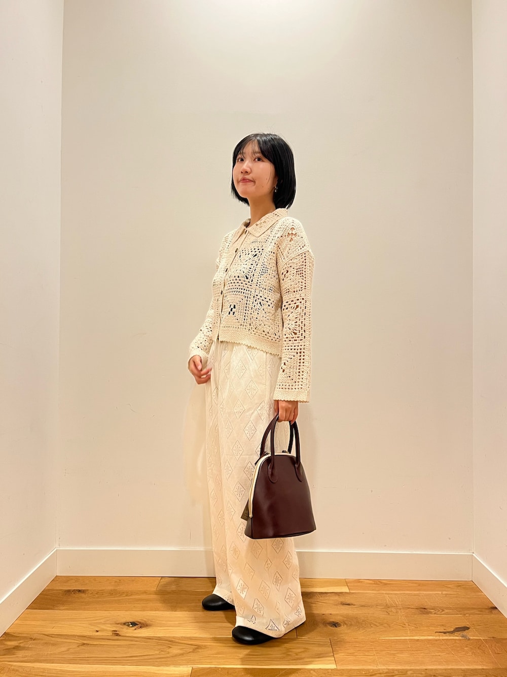 ベージュ系のカーディガン/ボレロ、ホワイト系のその他パンツ、レッド系のハンドバッグを着用したレディースの秋コーディネートの2枚目の写真