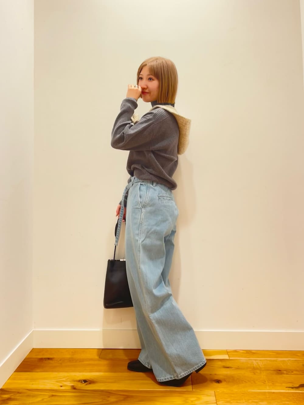 グレー系のニット/セーター、ブルー系のデニムパンツ、ブラック系のショルダーバッグを着用したレディースの冬コーディネートの2枚目の写真