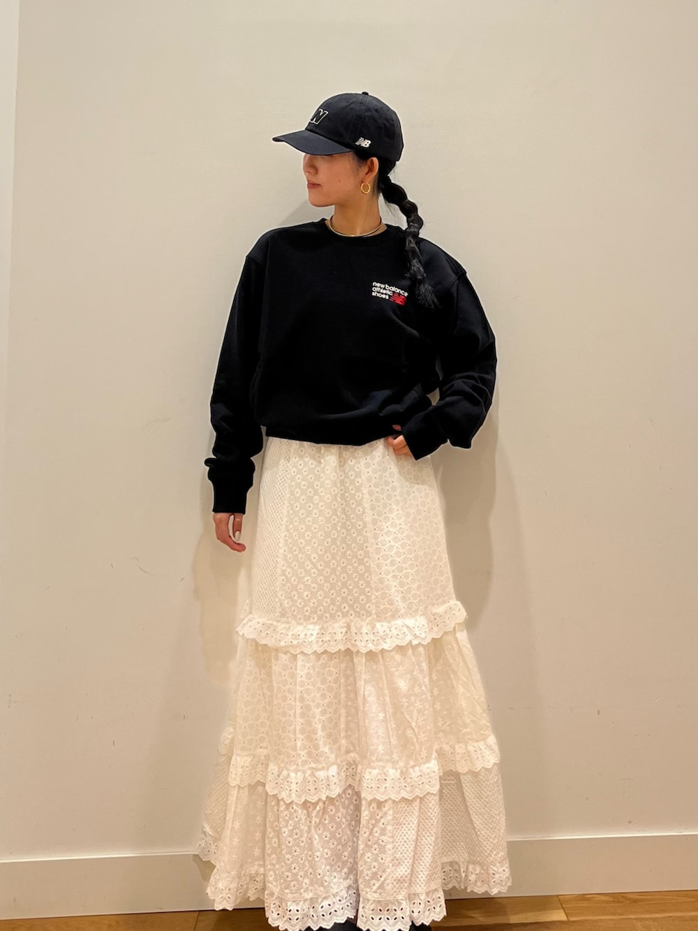 グレー系のスウェット、ホワイト系のスカート、ブラック系のキャップを着用したレディースの秋コーディネートの3枚目の写真