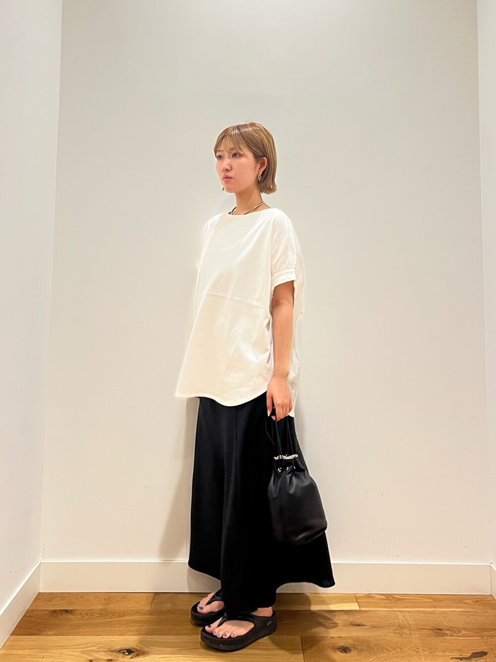 ブラック系のスカート、ホワイト系のTシャツ/カットソー、ブラック系のショルダーバッグを着用したレディースの夏コーディネートの2枚目の写真