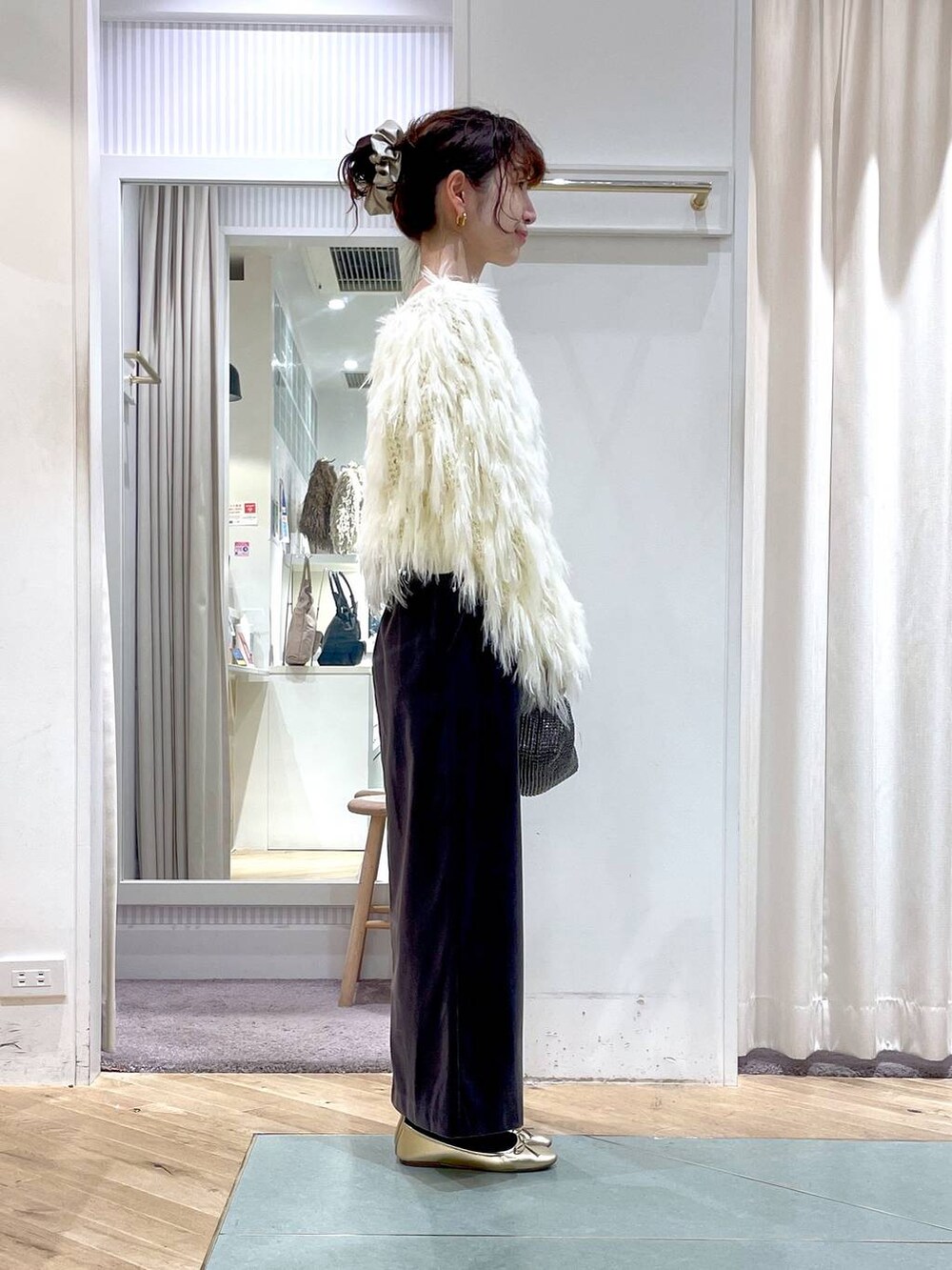 ブラウン系のスカート、ホワイト系のニット/セーター、ブラック系のハンドバッグを着用したレディースの冬コーディネートの2枚目の写真