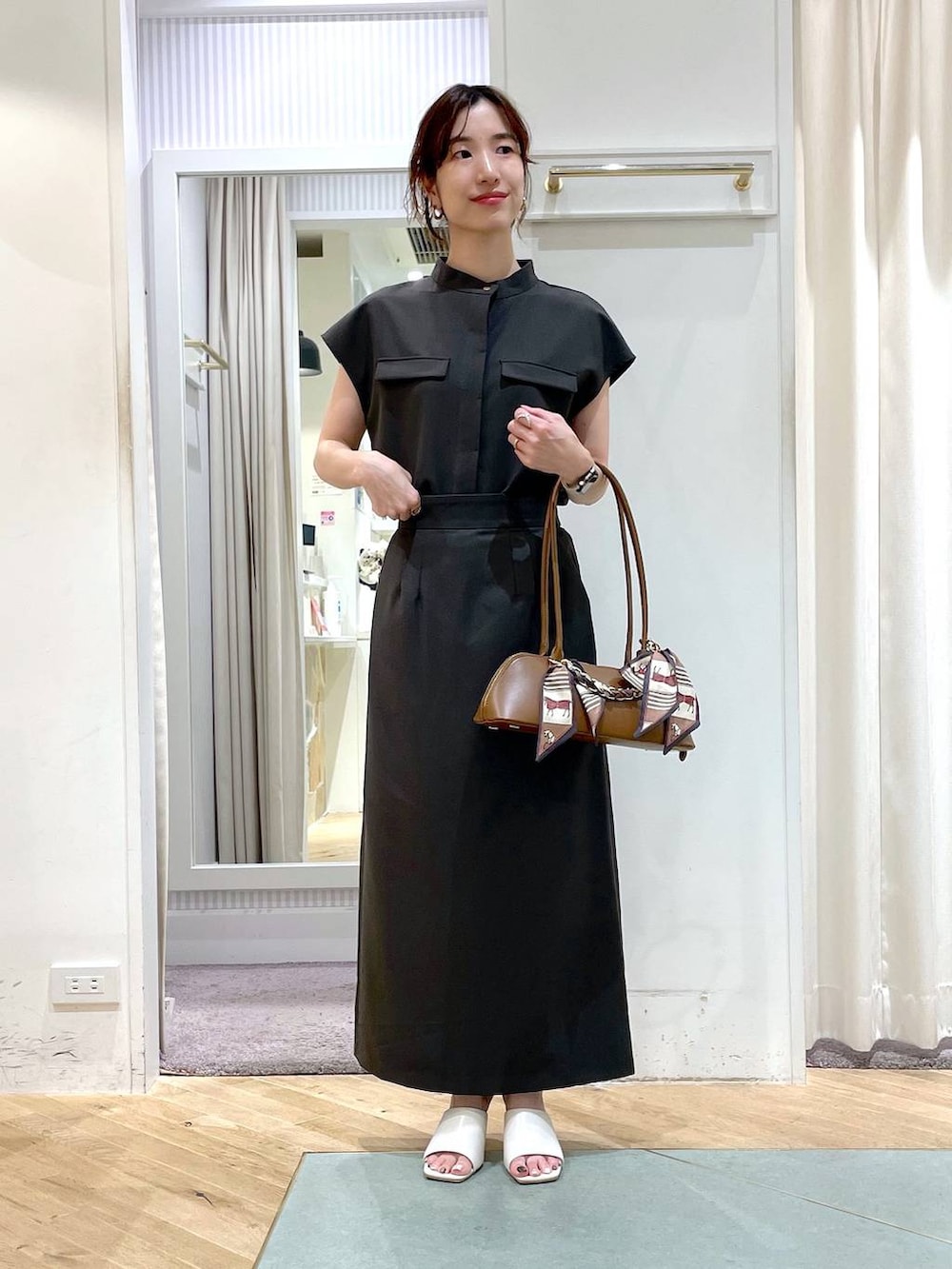 ブラウン系のボストンバッグ、グレー系のシャツ/ブラウス、グレー系のスカートを着用したレディースの夏コーディネートの3枚目の写真