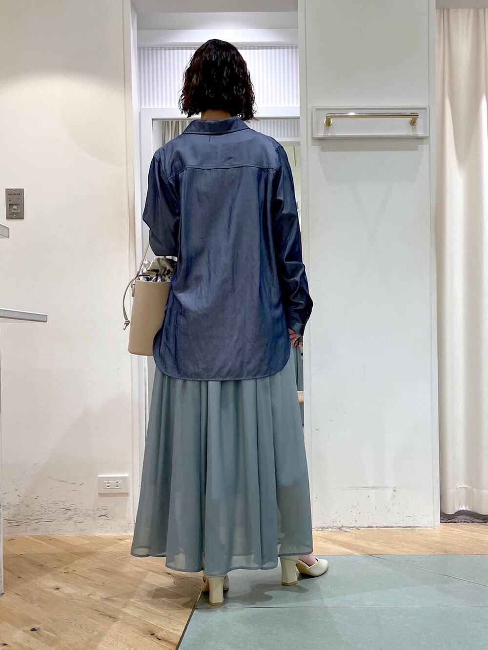 グリーン系のスカート、ホワイト系のパンプス、ブルー系のシャツ/ブラウスを着用したレディースの春コーディネートの3枚目の写真