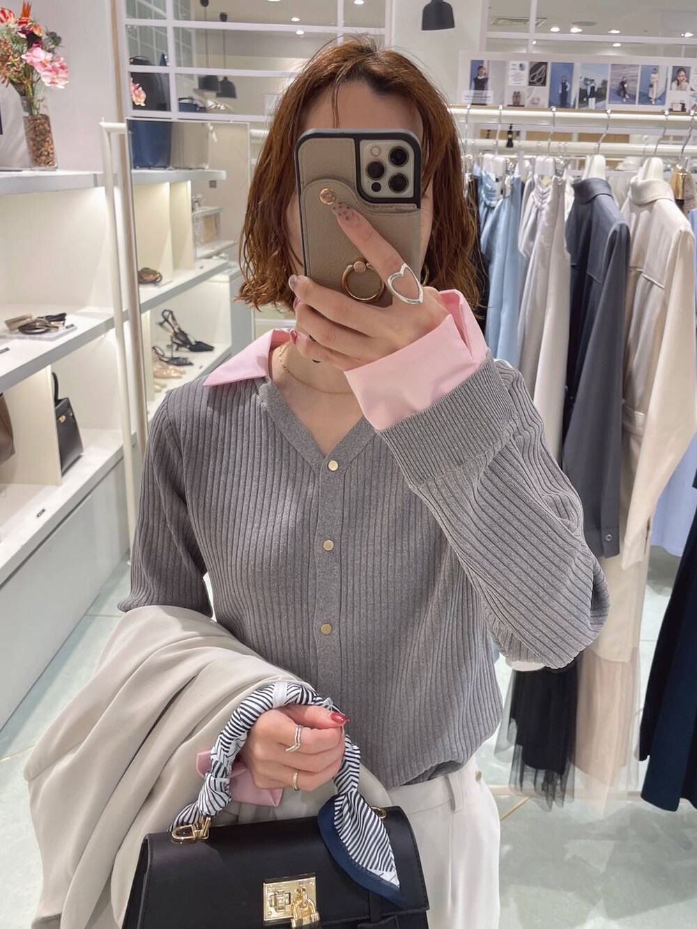 グレー系のニット/セーター、ブラック系のハンドバッグ、ベージュ系のスラックスを着用したレディースの冬コーディネートの3枚目の写真