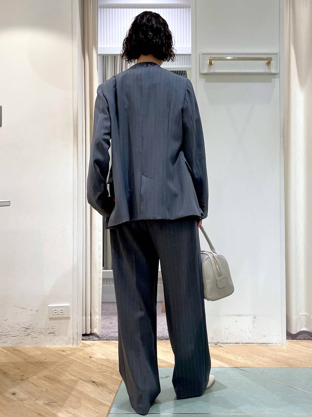 ホワイト系のパンプス、グレー系のスラックス、グレー系のノーカラージャケットを着用したレディースの春コーディネートの3枚目の写真