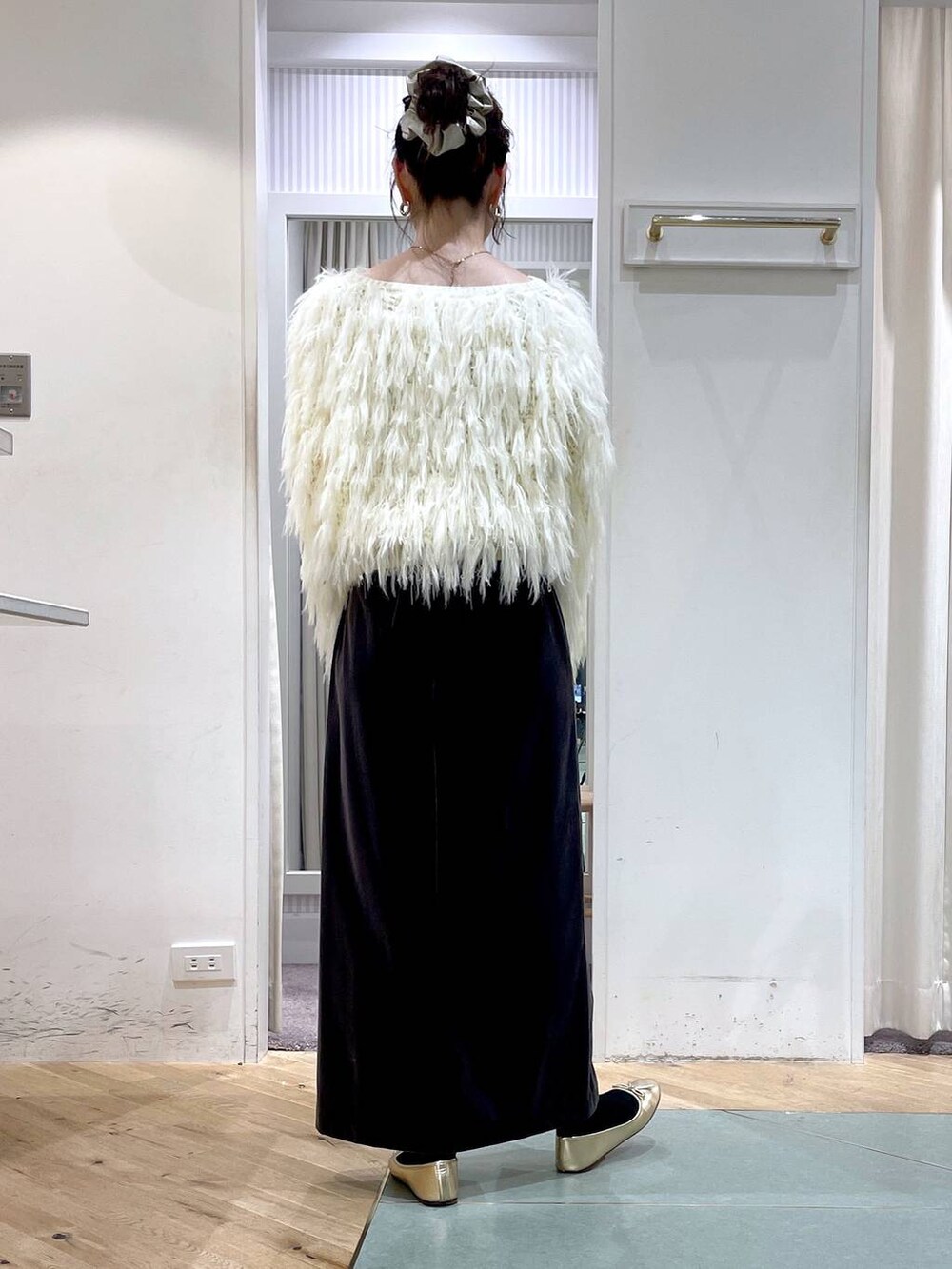 ブラウン系のスカート、ホワイト系のニット/セーター、ブラック系のハンドバッグを着用したレディースの冬コーディネートの3枚目の写真