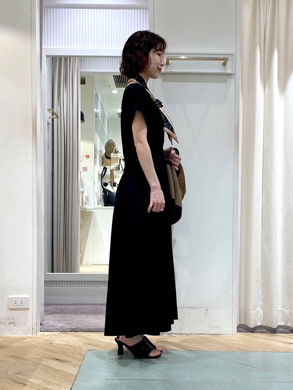 ブラック系のサンダル、ブラウン系のテーラードジャケット、ブラック系のワンピースを着用したレディースの春コーディネートの2枚目の写真