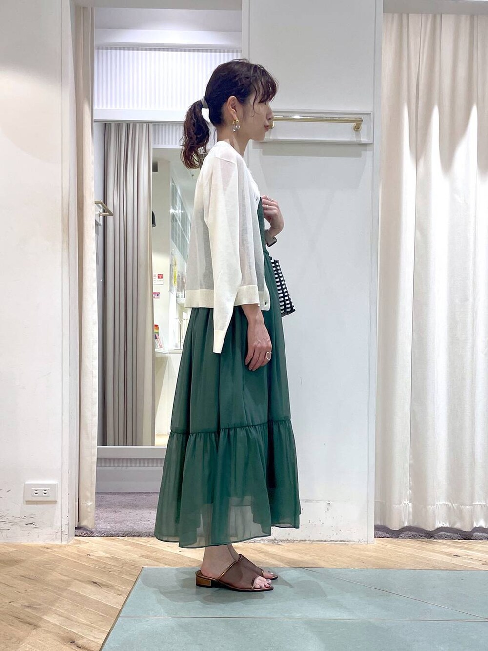 ブラック系のかごバッグ、ホワイト系のカーディガン/ボレロ、ホワイト系のニット/セーターを着用したレディースの夏コーディネートの2枚目の写真