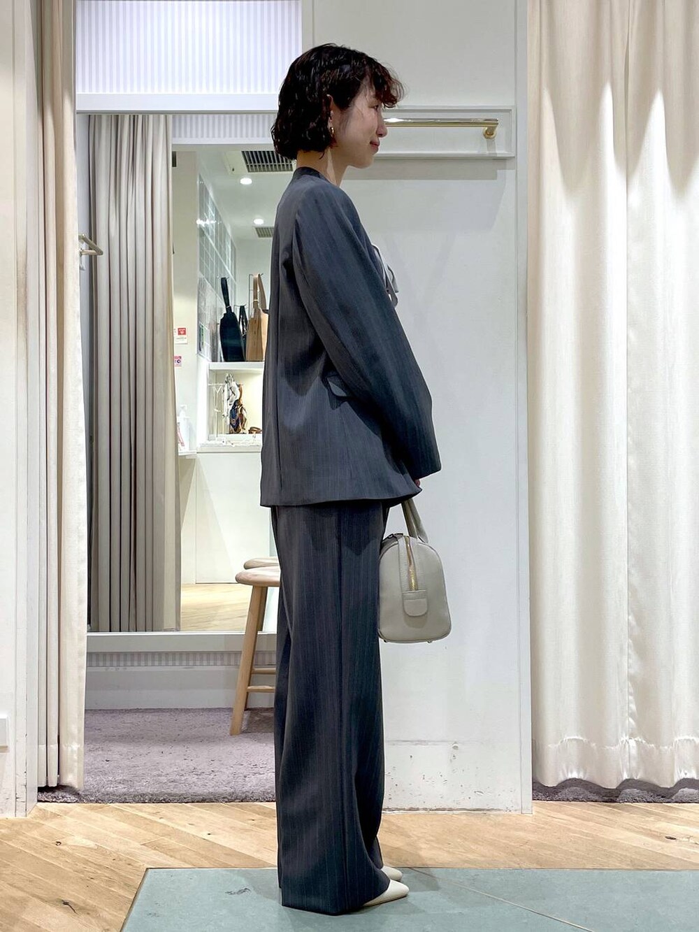 ホワイト系のパンプス、グレー系のスラックス、グレー系のノーカラージャケットを着用したレディースの春コーディネートの2枚目の写真