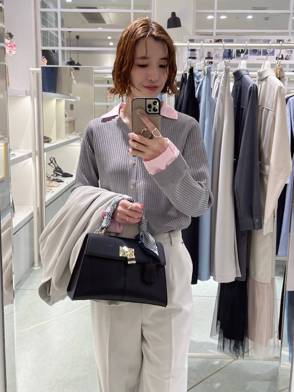 グレー系のニット/セーター、ブラック系のハンドバッグ、ベージュ系のスラックスを着用したレディースの冬コーディネートの2枚目の写真