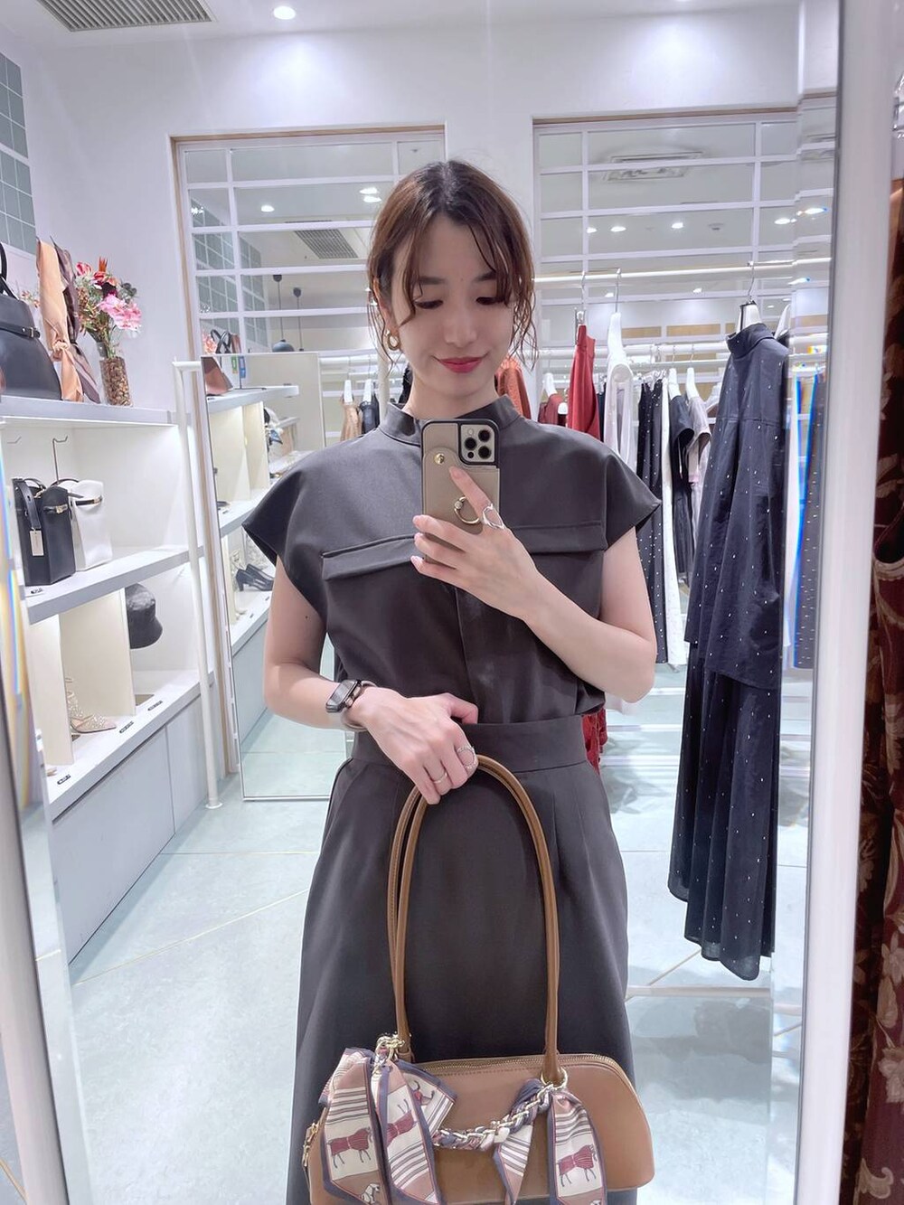 ブラウン系のボストンバッグ、グレー系のシャツ/ブラウス、グレー系のスカートを着用したレディースの夏コーディネートの2枚目の写真