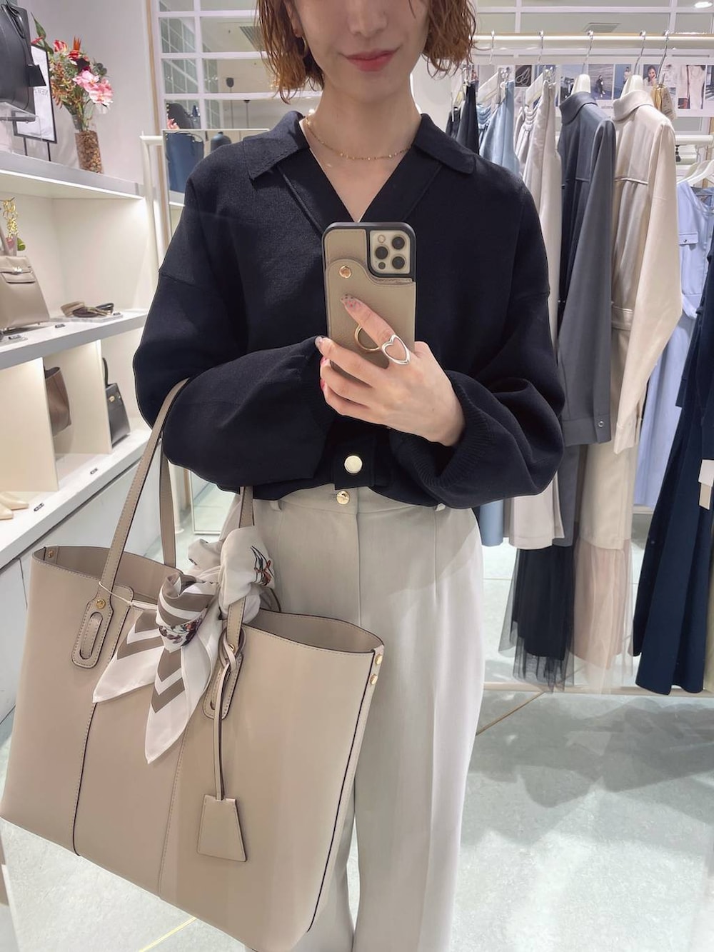 ブラック系のニット/セーター、ホワイト系のトートバッグ、ベージュ系のスラックスを着用したレディースの冬コーディネートの2枚目の写真