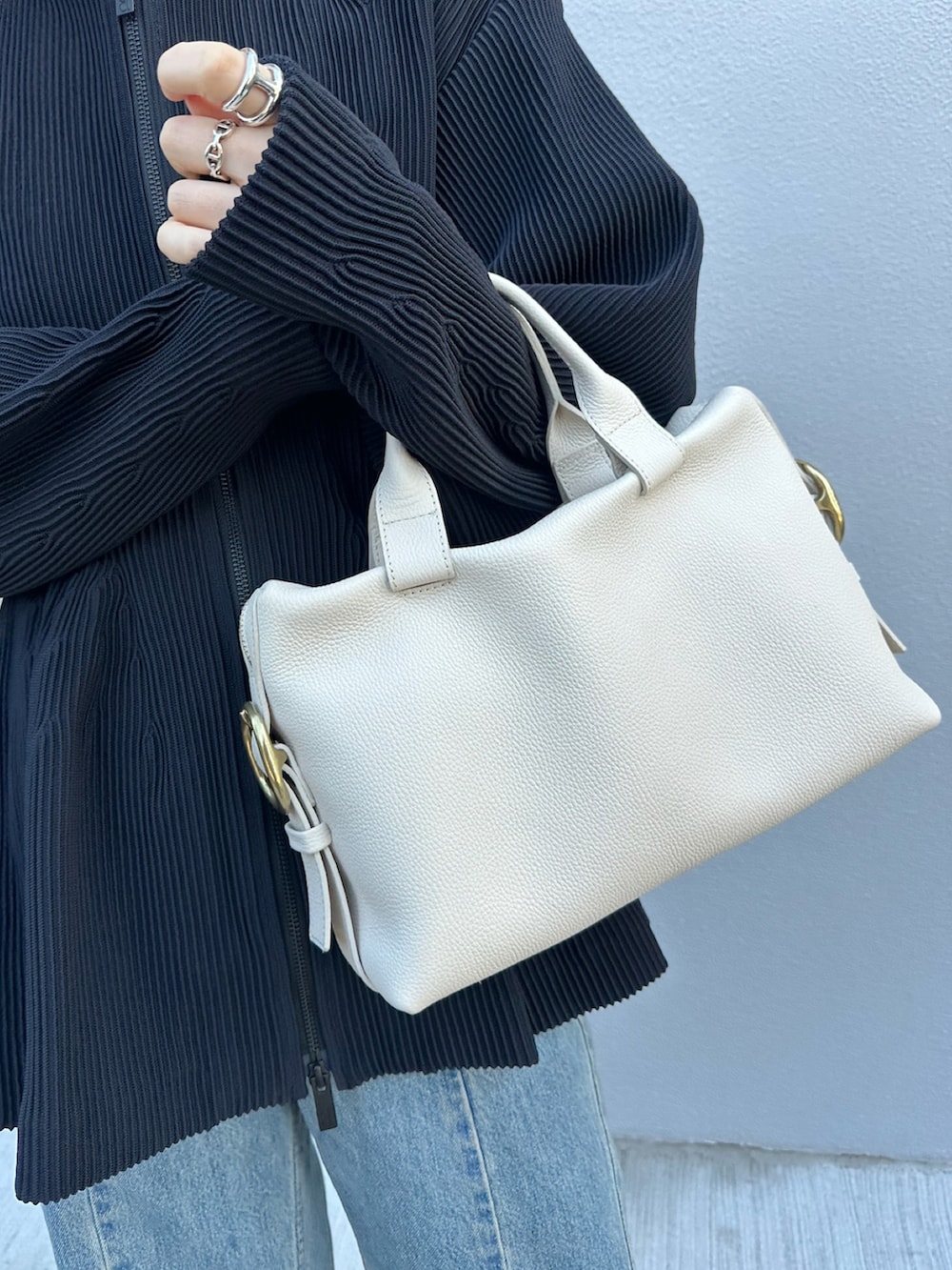 ホワイト系のボストンバッグ、ブラック系のトップス、ブルー系のデニムパンツを着用したレディースの春コーディネートの3枚目の写真