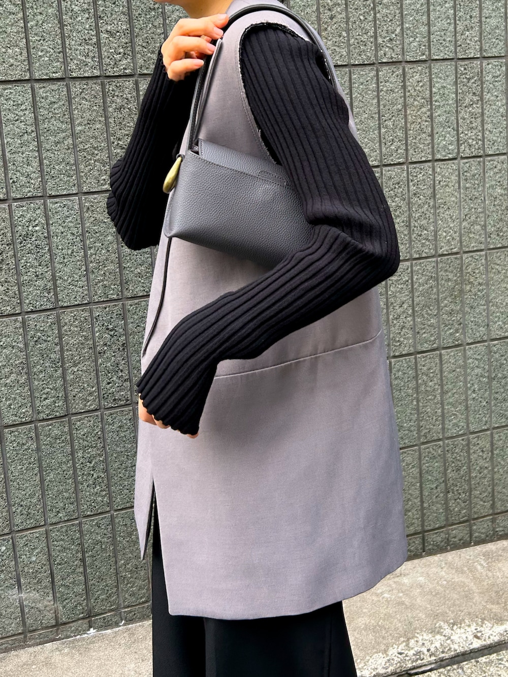 グレー系のハンドバッグ、シルバー系のパンプス、ブラック系のTシャツ/カットソーを着用したレディースの冬コーディネートの2枚目の写真