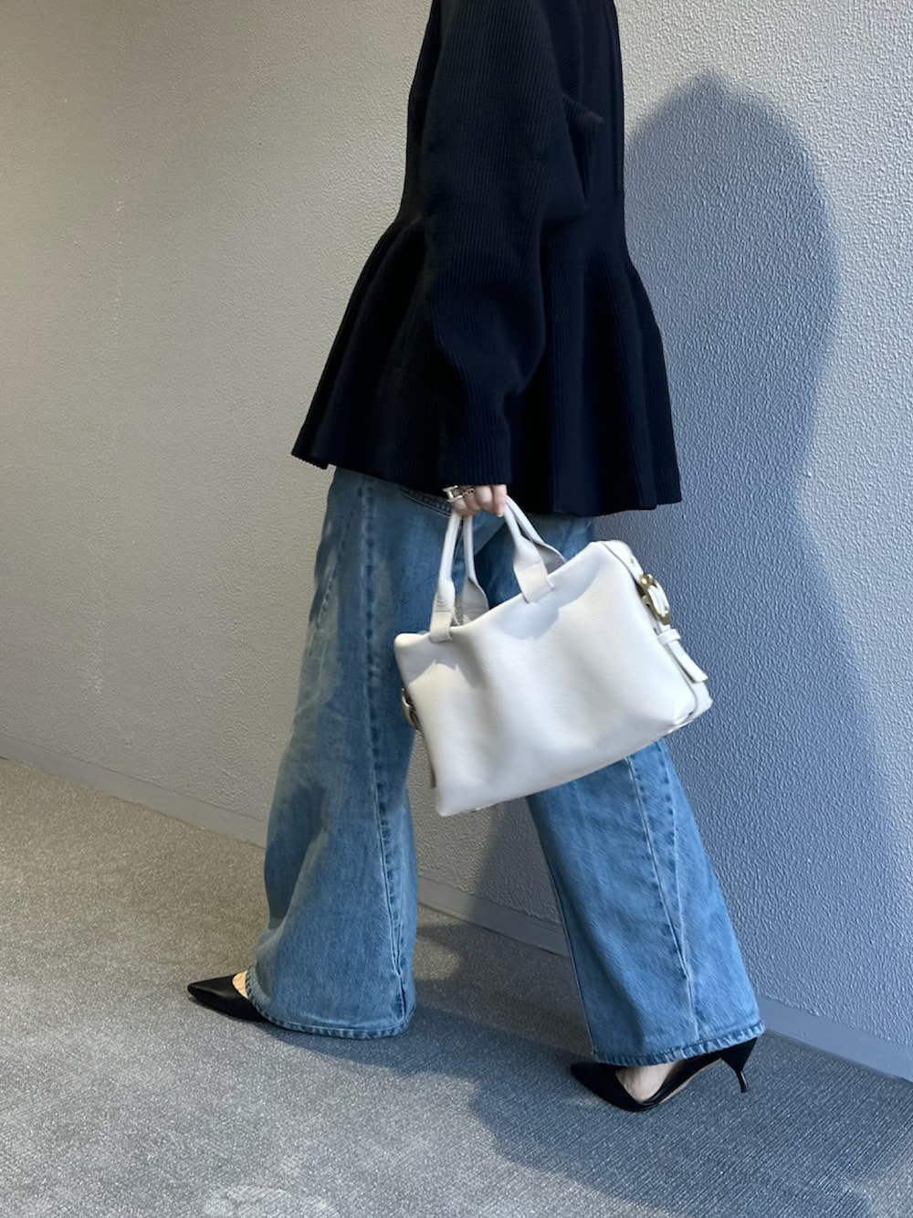 ホワイト系のボストンバッグ、ブラック系のトップス、ブルー系のデニムパンツを着用したレディースの春コーディネートの2枚目の写真