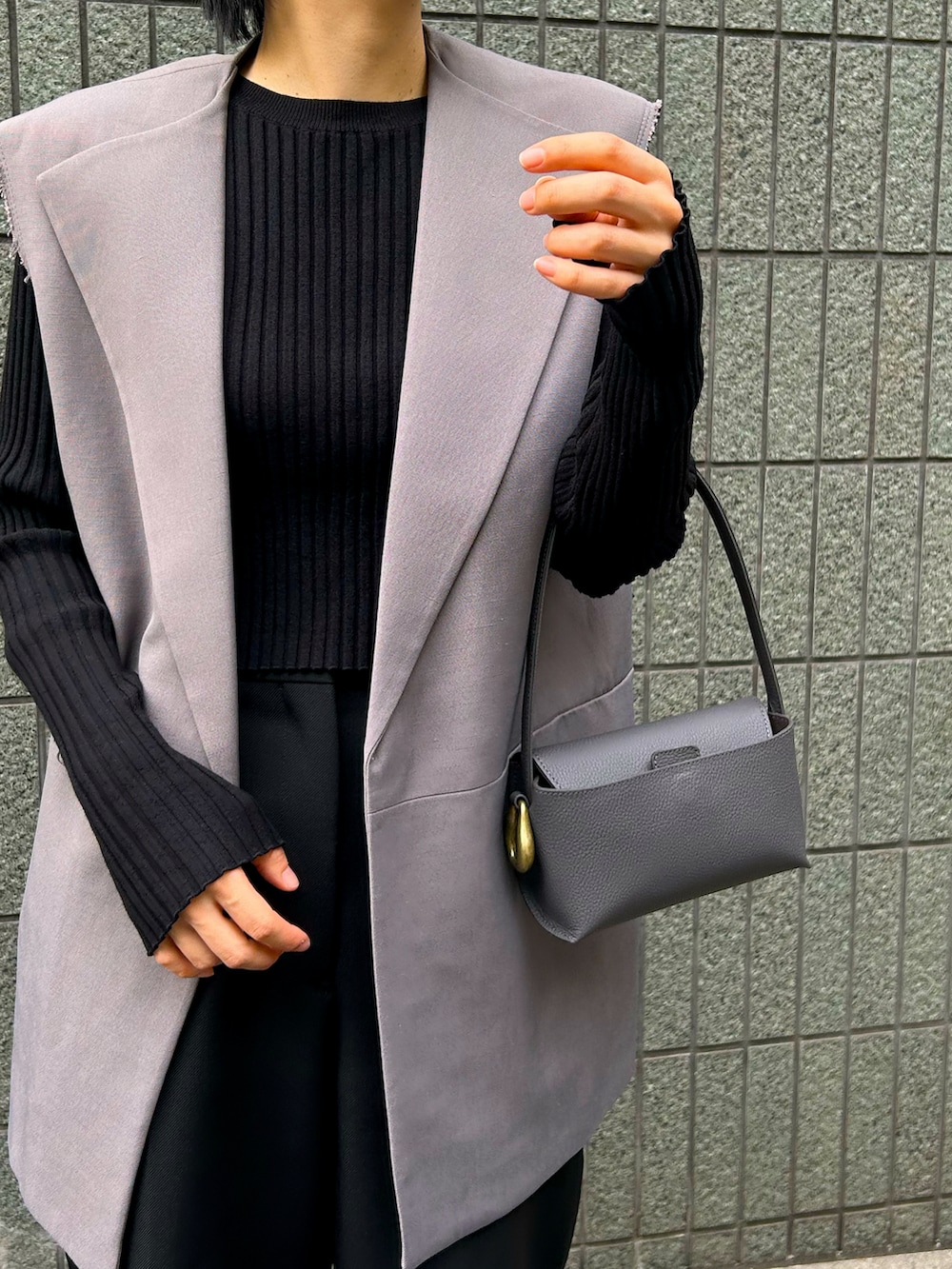 グレー系のハンドバッグ、シルバー系のパンプス、ブラック系のTシャツ/カットソーを着用したレディースの冬コーディネートの3枚目の写真