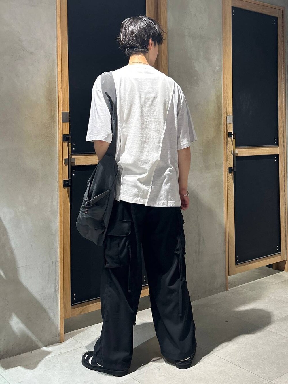 ブラック系のサンダル、ホワイト系のTシャツ/カットソー、ブラック系のカーゴパンツを着用したメンズの夏コーディネートの5枚目の写真