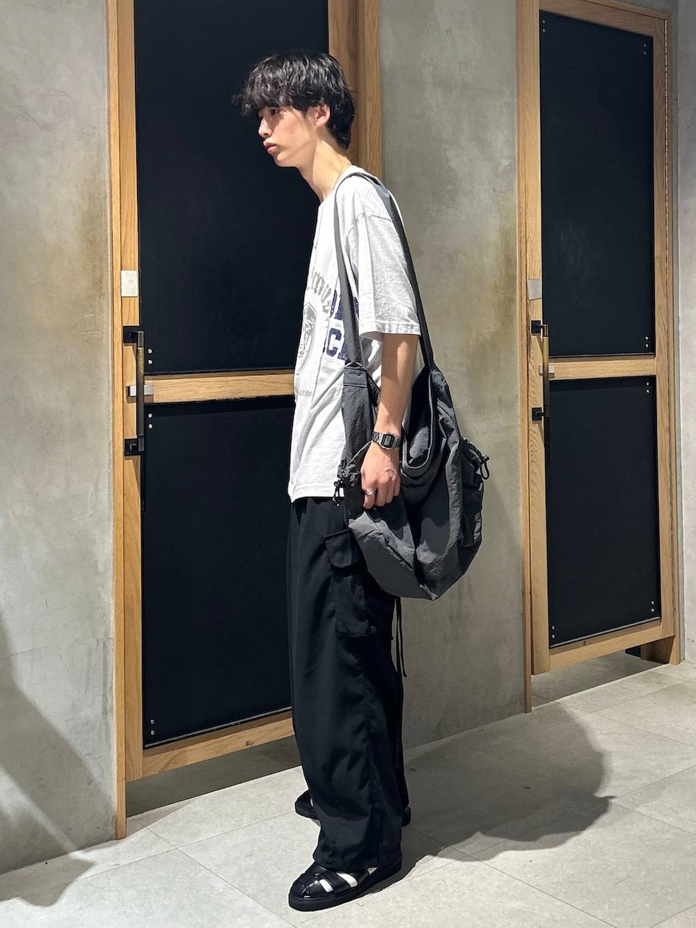 ブラック系のサンダル、ホワイト系のTシャツ/カットソー、ブラック系のカーゴパンツを着用したメンズの夏コーディネートの3枚目の写真