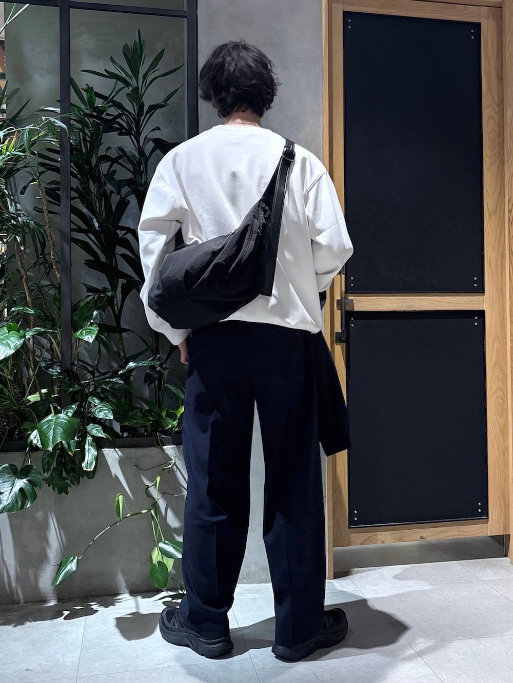 ブラック系のスニーカー、ブルー系のスラックス、ブラック系のショルダーバッグを着用したメンズの春コーディネートの5枚目の写真