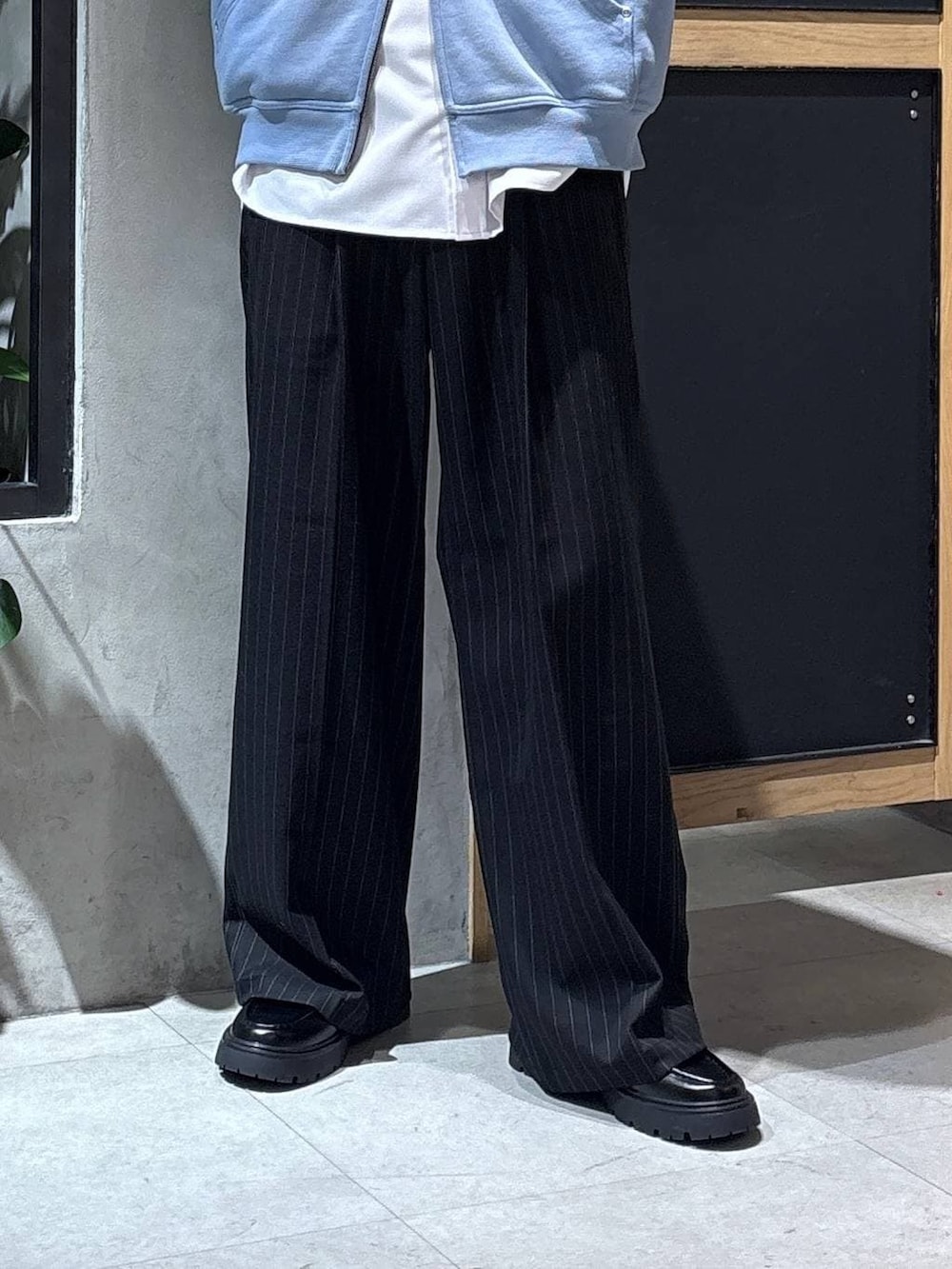 ブラック系のスラックス、ブラック系のドレスシューズ、ブルー系のパーカーを着用したメンズの冬コーディネートの3枚目の写真