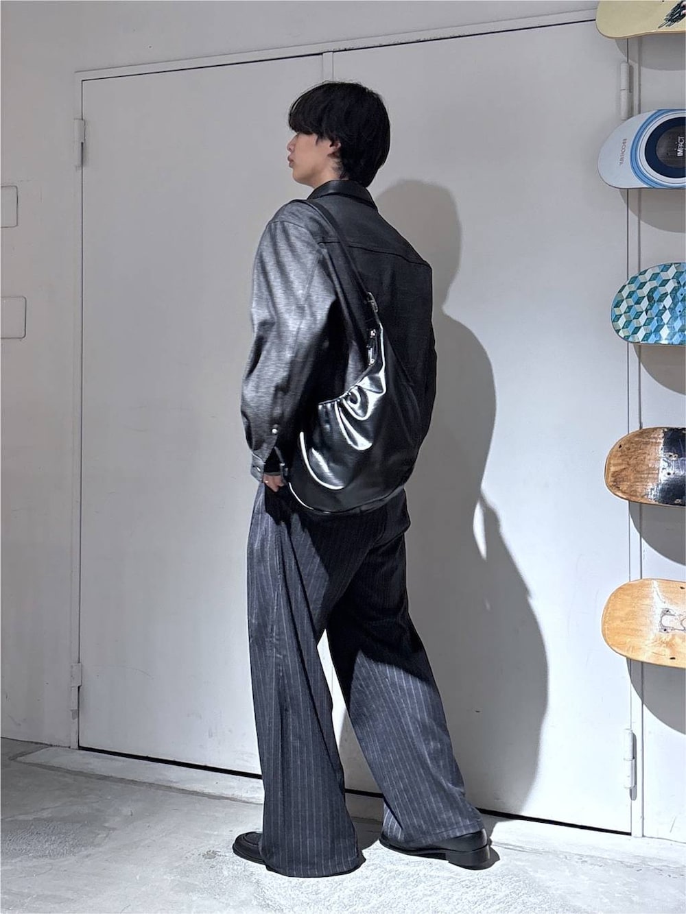 ブラック系のショルダーバッグ、ブラック系のデニムジャケット、グレー系のスラックスを着用したメンズの秋コーディネートの4枚目の写真