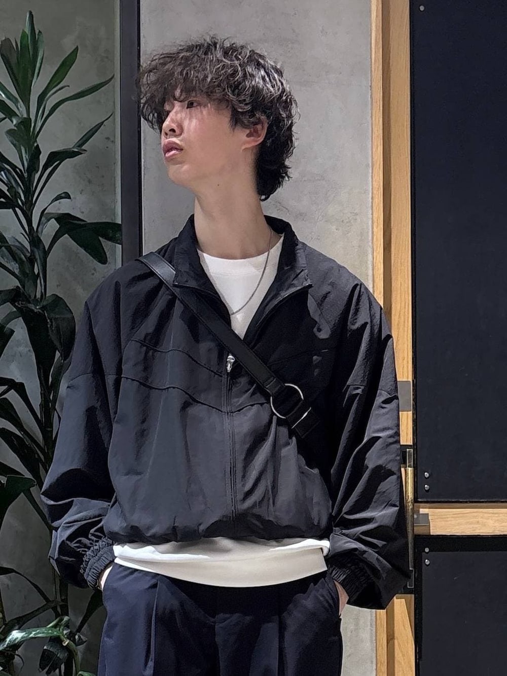 ブラック系のスニーカー、ブルー系のスラックス、ブラック系のショルダーバッグを着用したメンズの春コーディネートの7枚目の写真