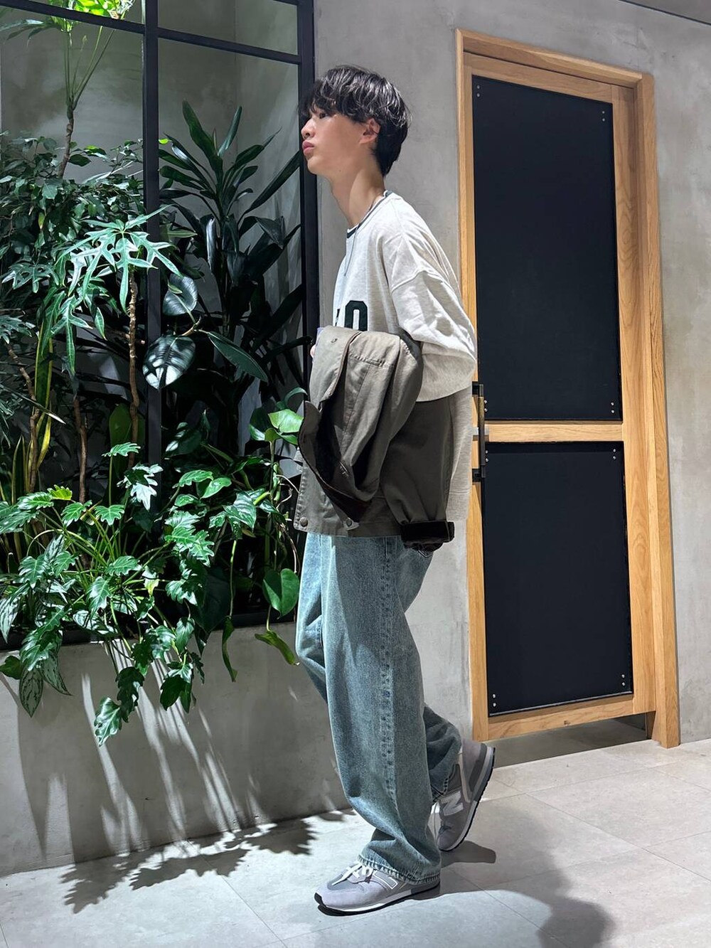 グレー系のスニーカー、ブルー系のデニムパンツ、グリーン系のブルゾンを着用したメンズの秋コーディネートの7枚目の写真