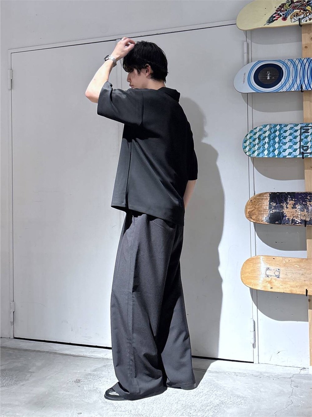 ブラック系のTシャツ/カットソー、ブラック系のローファー、ブラック系のスラックスを着用したメンズの夏コーディネートの4枚目の写真