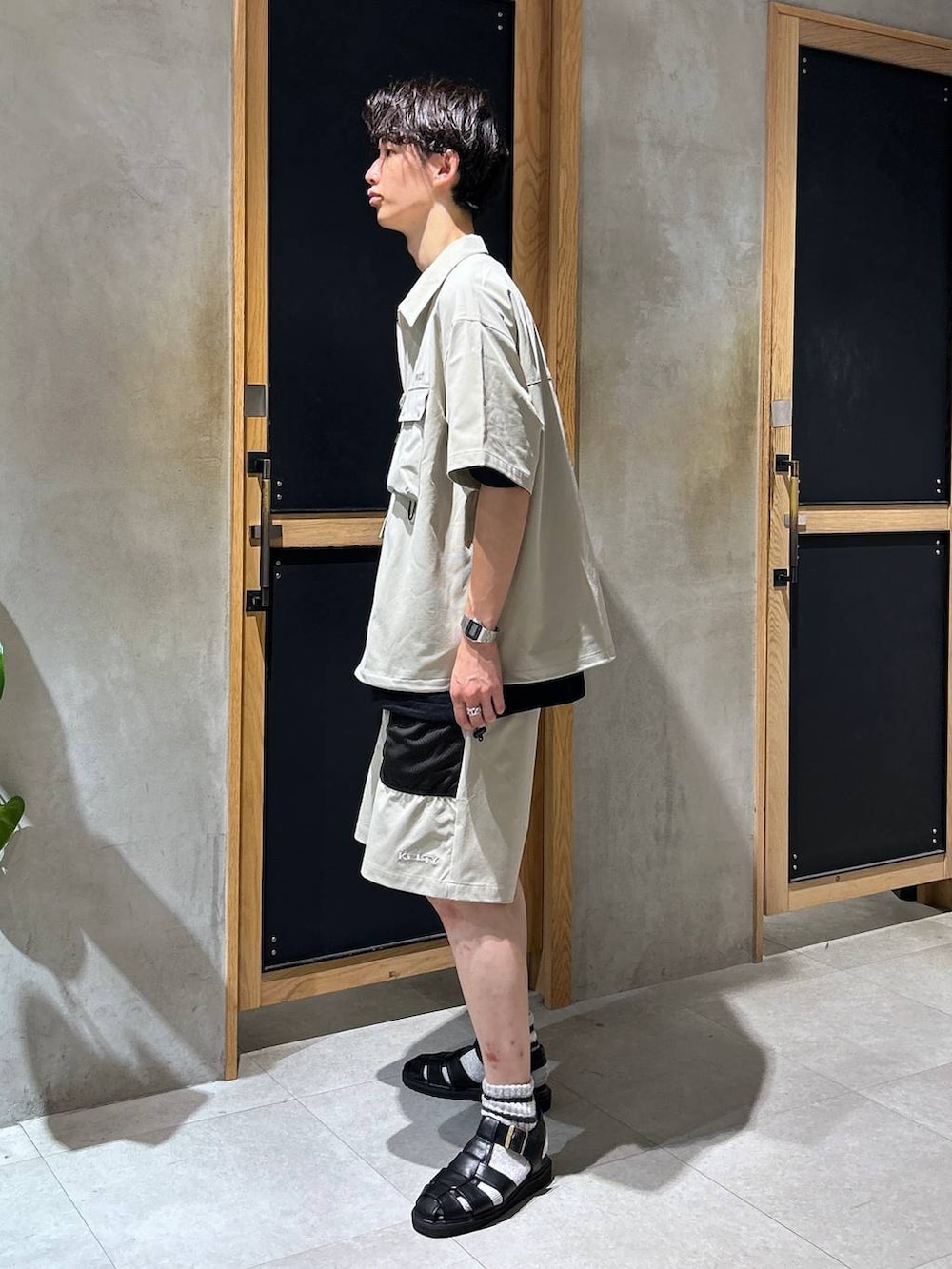 ブラック系のサンダル、ブラック系のTシャツ/カットソー、グレー系のチノパンツを着用したメンズの夏コーディネートの2枚目の写真