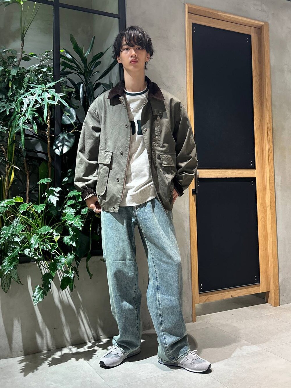 グレー系のスニーカー、ブルー系のデニムパンツ、グリーン系のブルゾンを着用したメンズの秋コーディネートの3枚目の写真