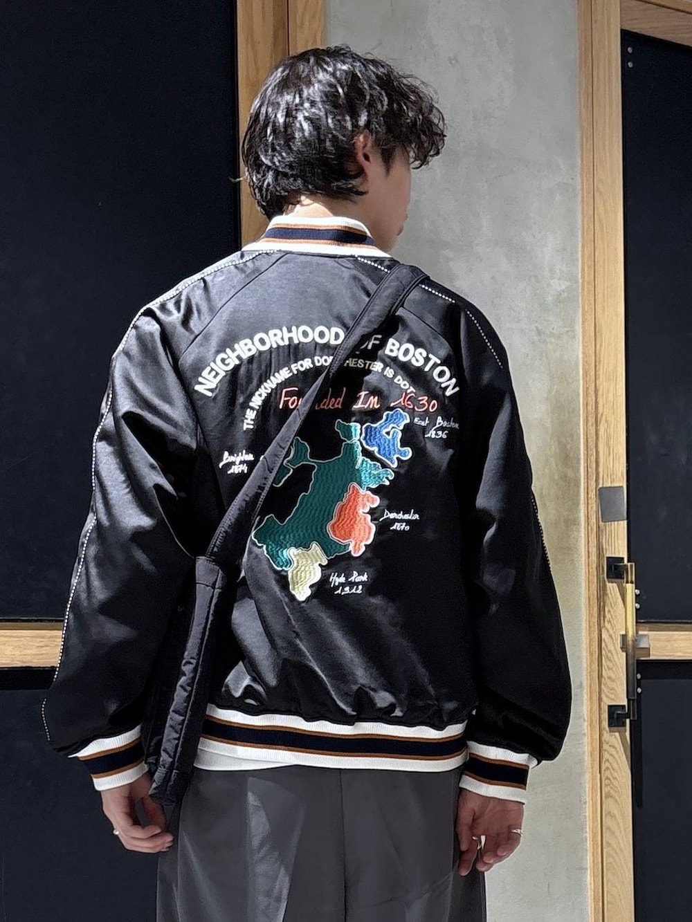 ブラック系のスニーカー、ブラック系のショルダーバッグ、グレー系のスラックスを着用したメンズの春コーディネートの2枚目の写真