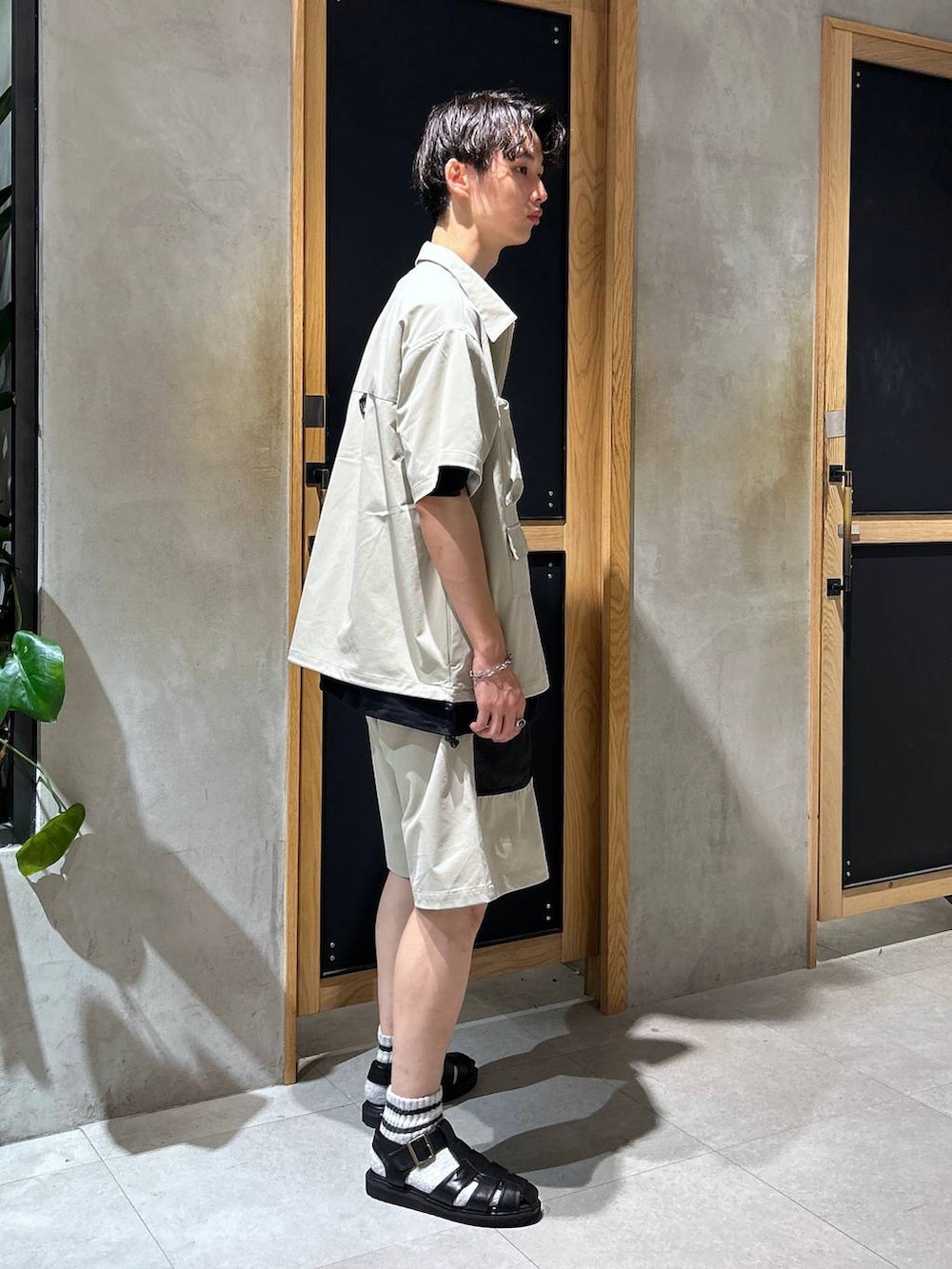 ブラック系のサンダル、ブラック系のTシャツ/カットソー、グレー系のチノパンツを着用したメンズの夏コーディネートの3枚目の写真