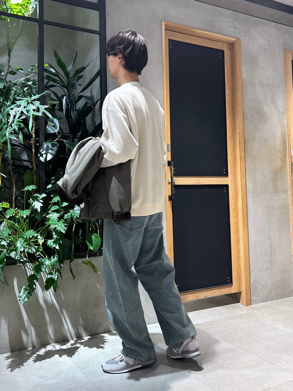 グレー系のスニーカー、ブルー系のデニムパンツ、グリーン系のブルゾンを着用したメンズの秋コーディネートの4枚目の写真