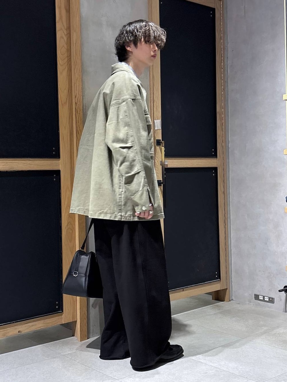 ブラック系のボストンバッグ、ブラック系のローファー、グリーン系のミリタリージャケットを着用したメンズの春コーディネートの9枚目の写真