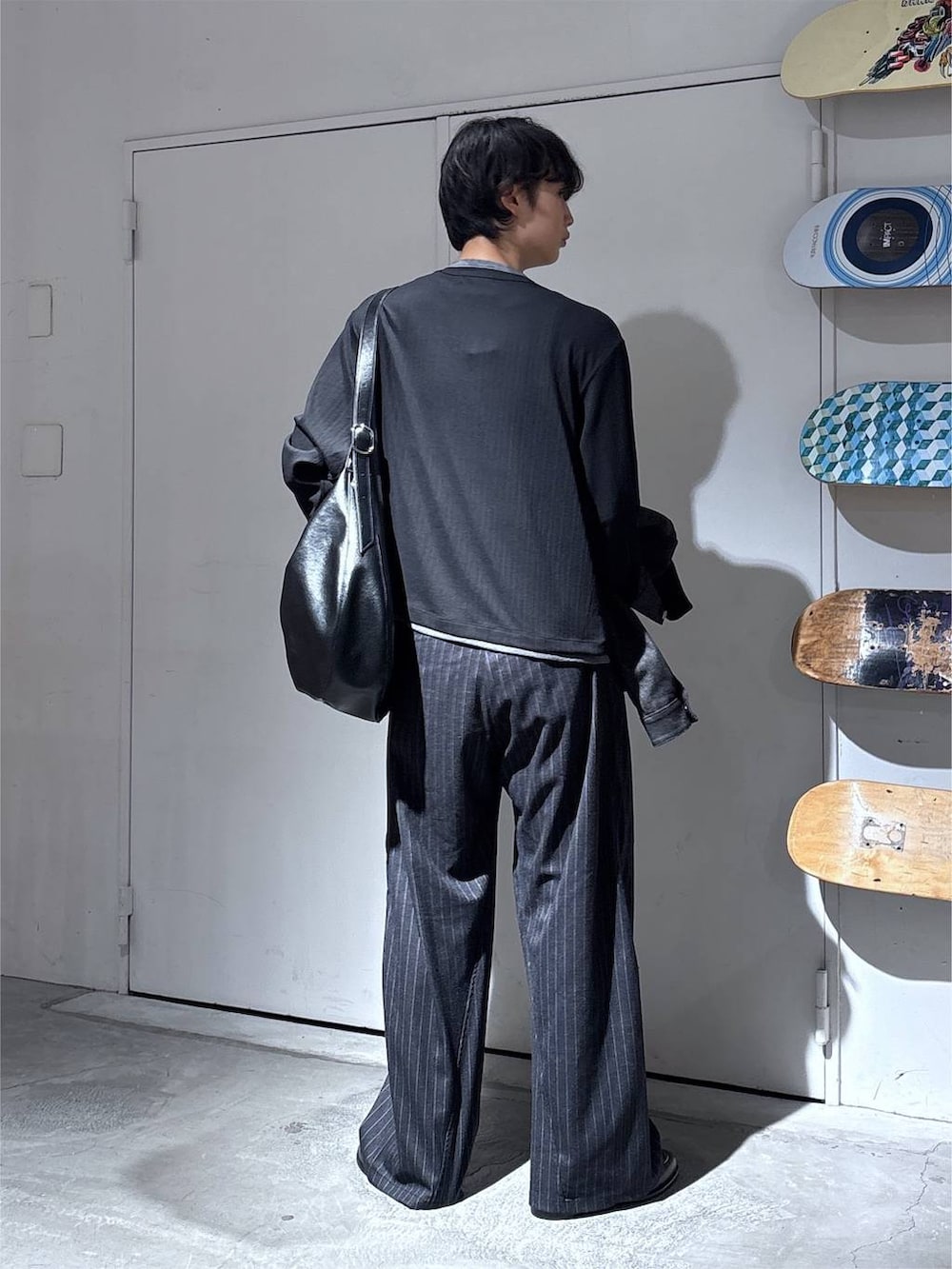 ブラック系のショルダーバッグ、ブラック系のデニムジャケット、グレー系のスラックスを着用したメンズの秋コーディネートの9枚目の写真