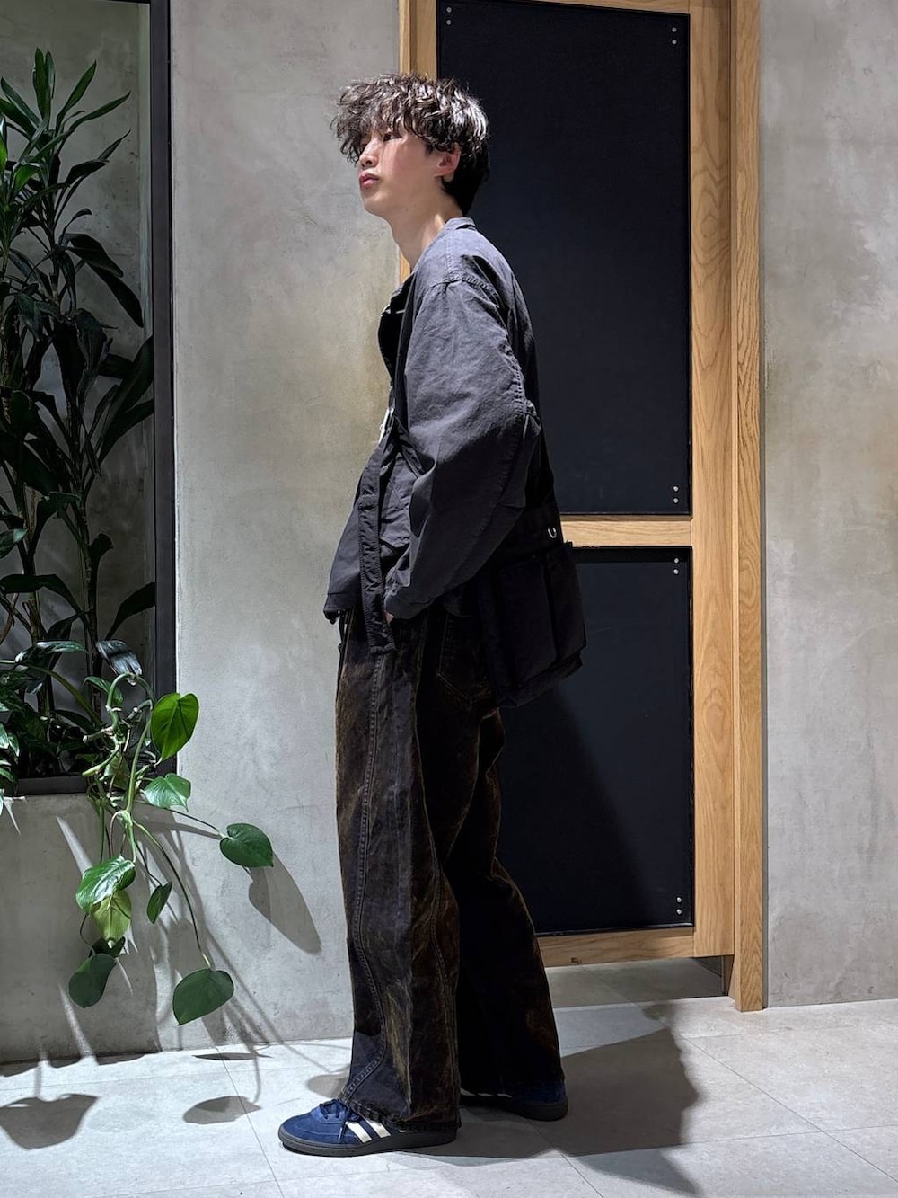 ブラック系のショルダーバッグ、ブラック系のモッズコート、ブルー系のスニーカーを着用したメンズの春コーディネートの4枚目の写真