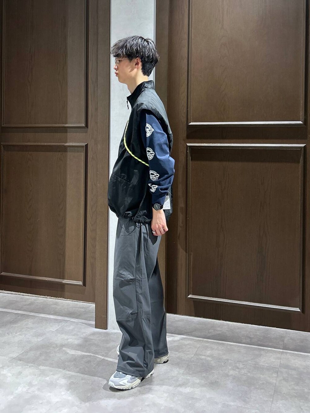 ブラック系のベスト、ブルー系のTシャツ/カットソー、グレー系のスウェットパンツを着用したメンズの春コーディネートの2枚目の写真