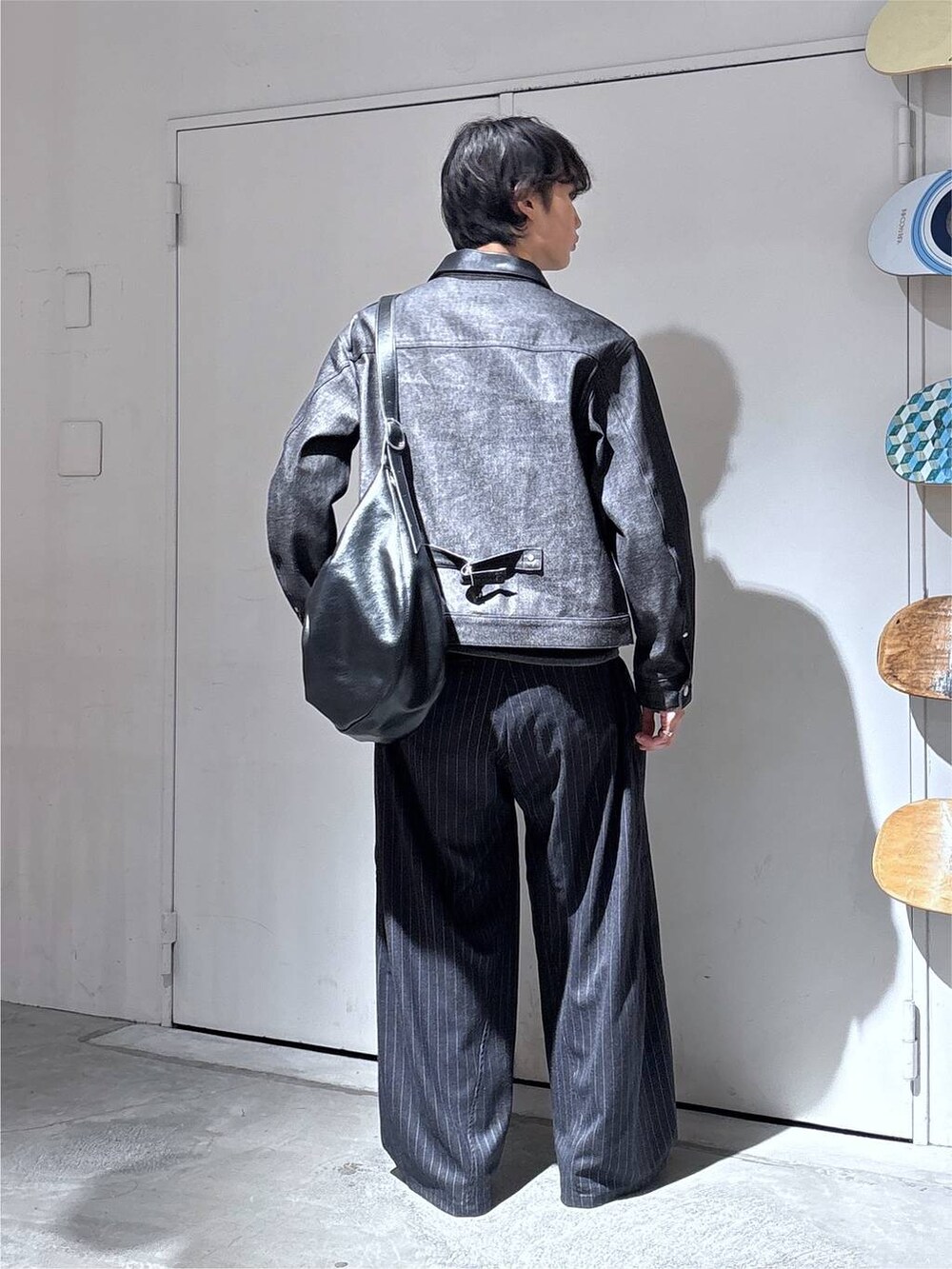 ブラック系のショルダーバッグ、ブラック系のデニムジャケット、グレー系のスラックスを着用したメンズの秋コーディネートの5枚目の写真