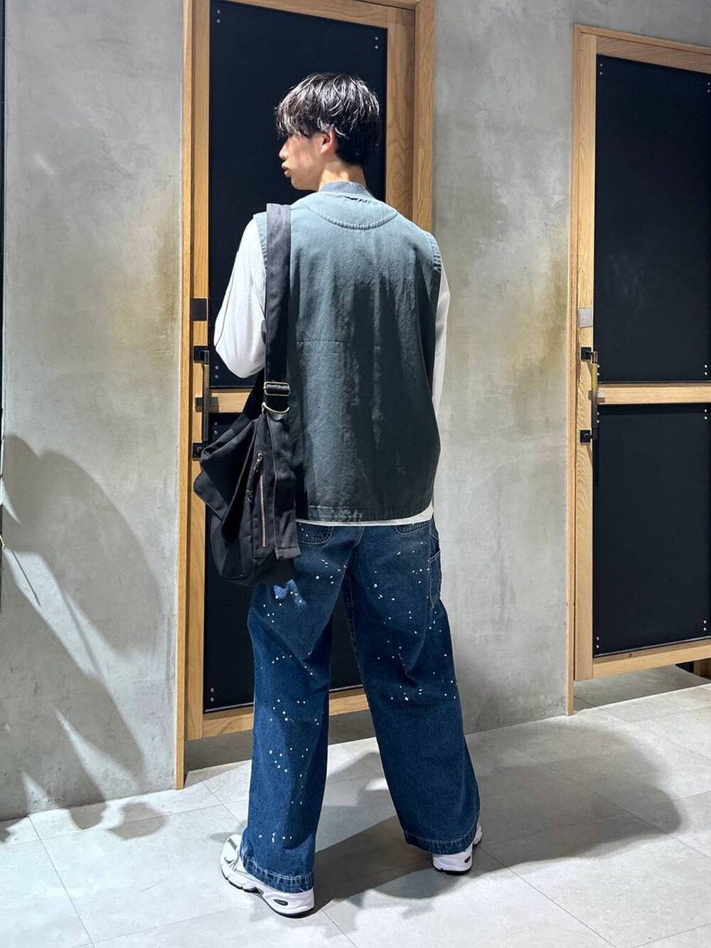 ホワイト系のスニーカー、ブルー系のデニムパンツ、ブラック系のショルダーバッグを着用したメンズの秋コーディネートの5枚目の写真