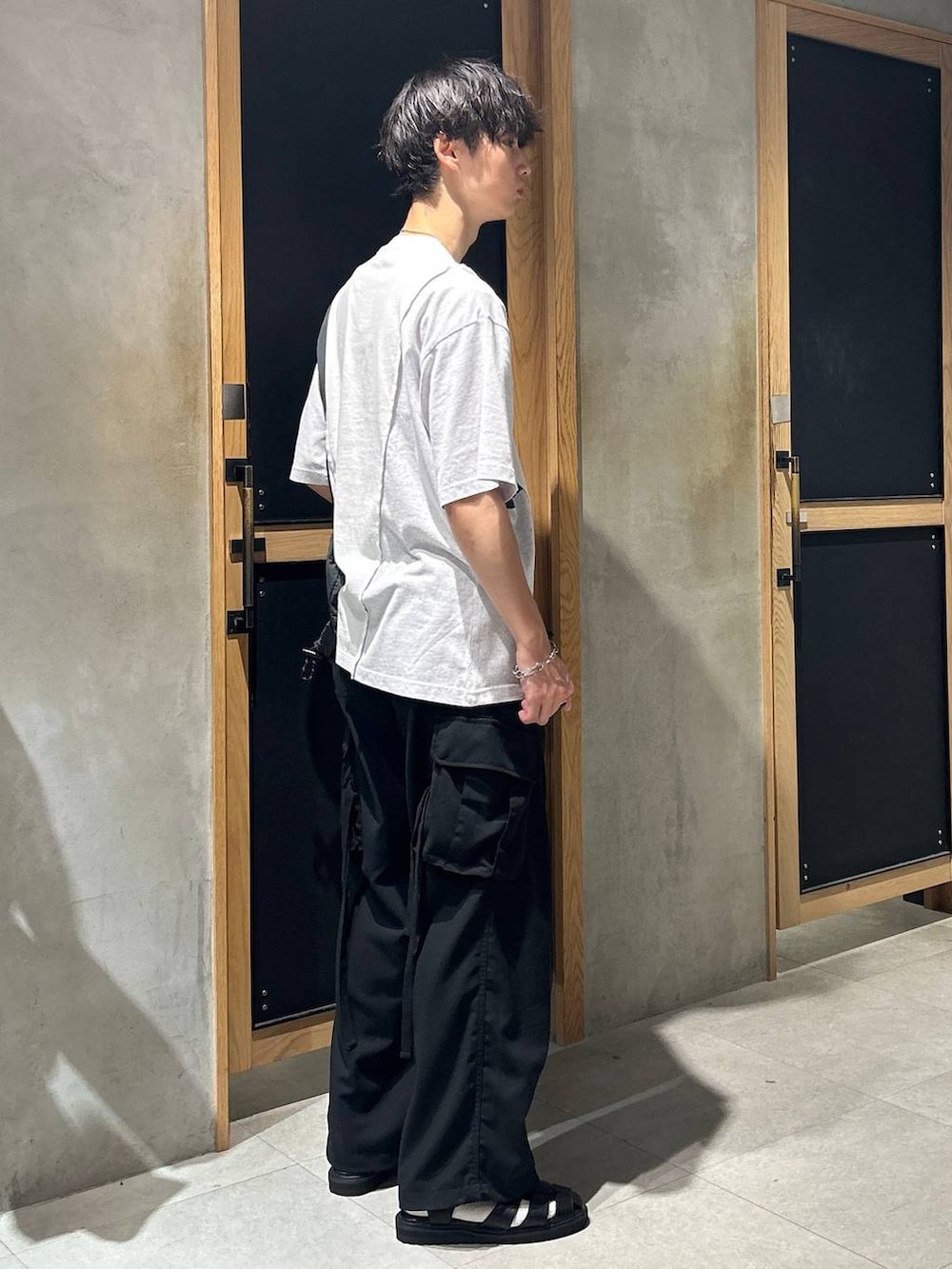 ブラック系のサンダル、ホワイト系のTシャツ/カットソー、ブラック系のカーゴパンツを着用したメンズの夏コーディネートの4枚目の写真