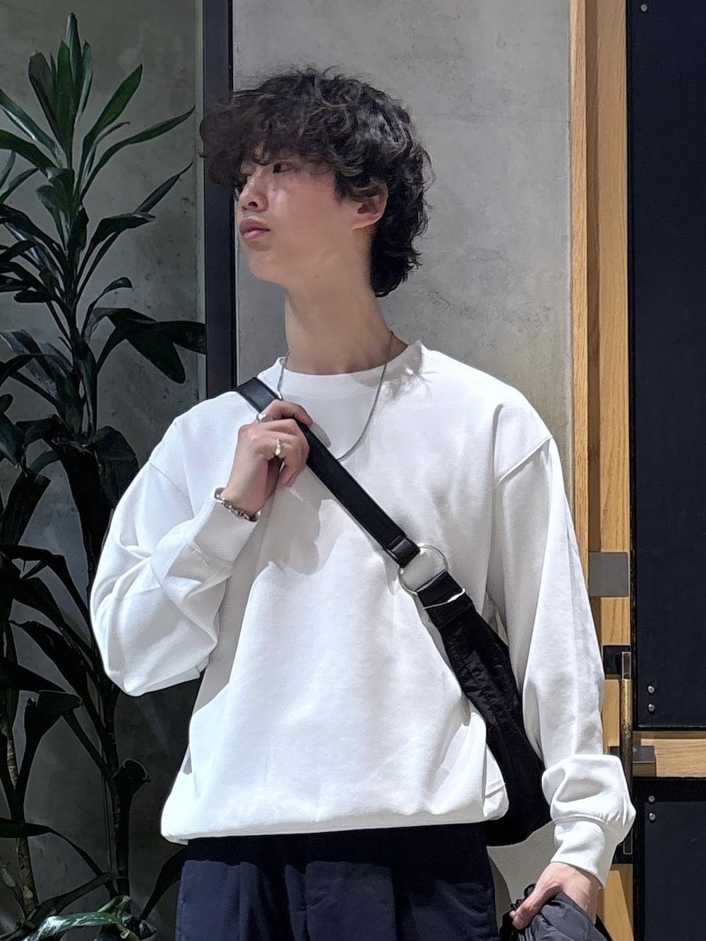 ブラック系のスニーカー、ブルー系のスラックス、ブラック系のショルダーバッグを着用したメンズの春コーディネートの2枚目の写真