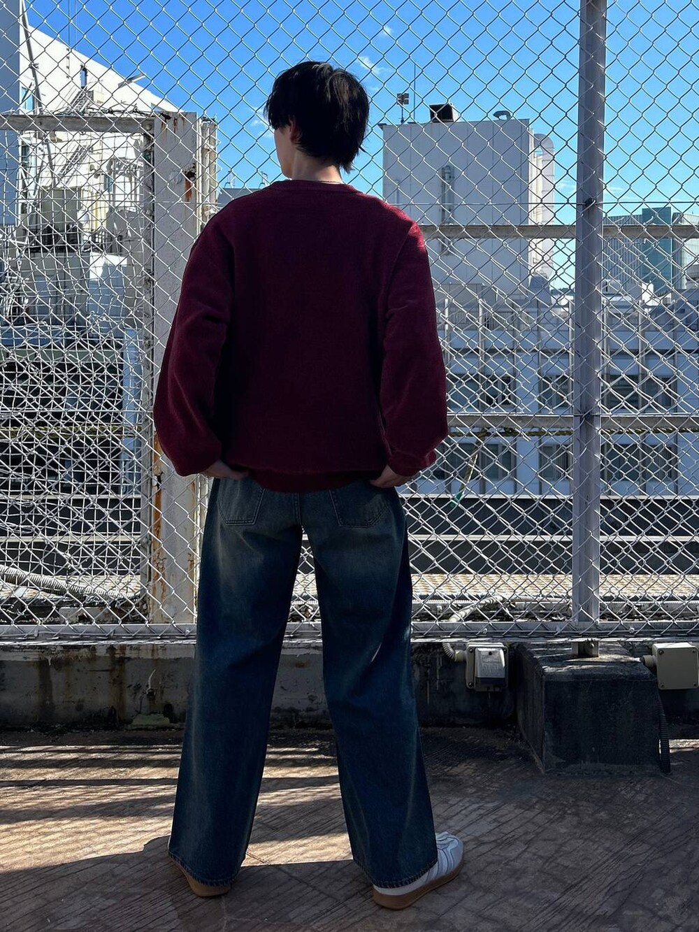 レッド系のニット/セーター、ホワイト系のTシャツ/カットソー、ブルー系のデニムパンツを着用したメンズの冬コーディネートの5枚目の写真