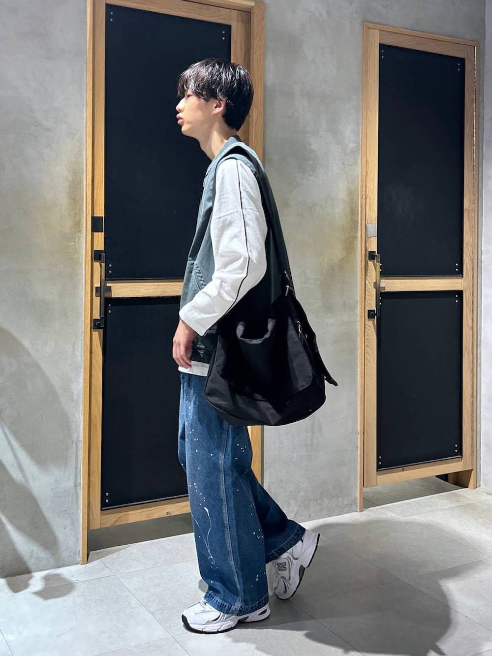 ホワイト系のスニーカー、ブルー系のデニムパンツ、ブラック系のショルダーバッグを着用したメンズの秋コーディネートの4枚目の写真