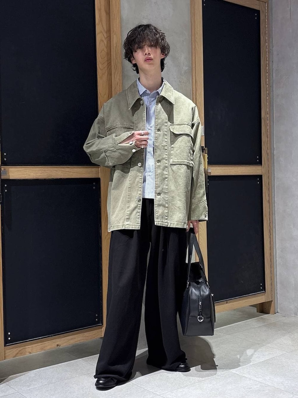 ブラック系のボストンバッグ、ブラック系のローファー、グリーン系のミリタリージャケットを着用したメンズの春コーディネートの6枚目の写真