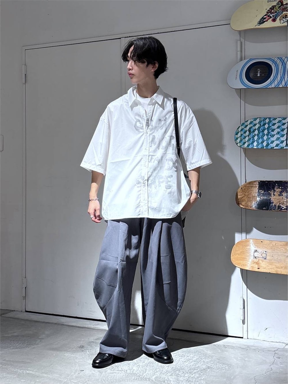 ホワイト系のシャツ/ブラウス、グレー系のスラックス、ブラック系のローファーを着用したメンズの夏コーディネートの2枚目の写真