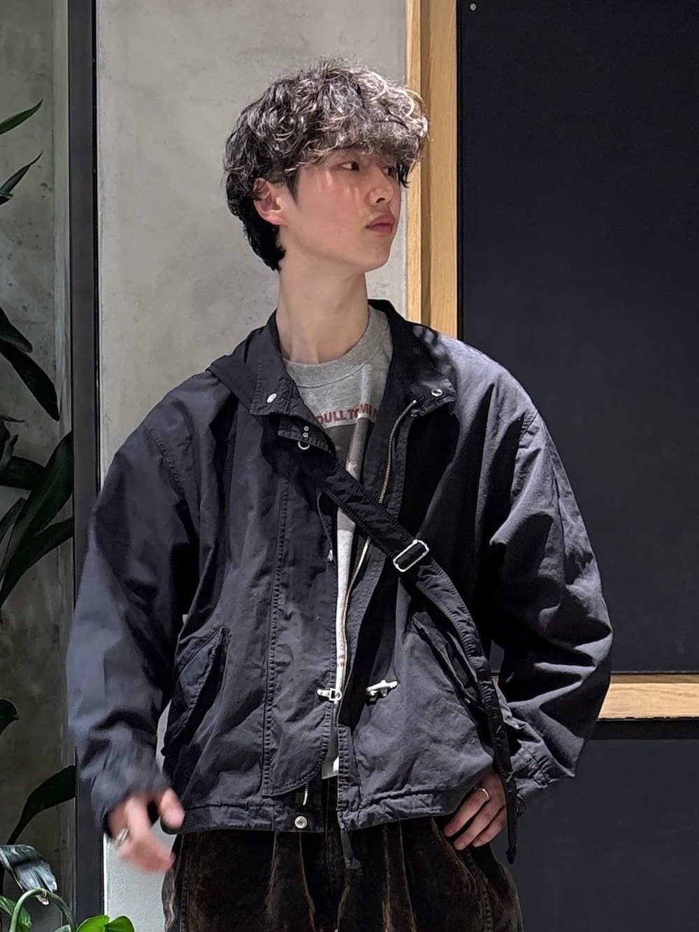 ブラック系のショルダーバッグ、ブラック系のモッズコート、ブルー系のスニーカーを着用したメンズの春コーディネートの2枚目の写真