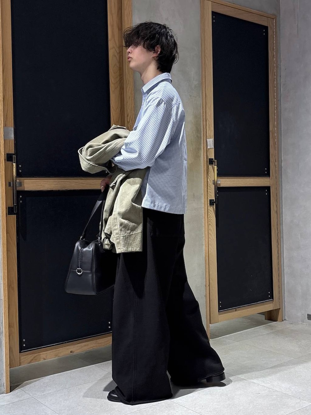 ブラック系のボストンバッグ、ブラック系のローファー、グリーン系のミリタリージャケットを着用したメンズの春コーディネートの4枚目の写真