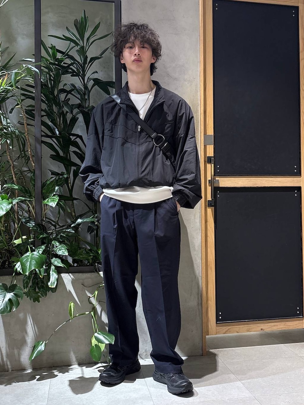 ブラック系のスニーカー、ブルー系のスラックス、ブラック系のショルダーバッグを着用したメンズの春コーディネートの6枚目の写真