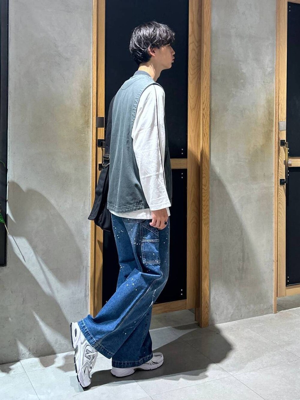 ホワイト系のスニーカー、ブルー系のデニムパンツ、ブラック系のショルダーバッグを着用したメンズの秋コーディネートの3枚目の写真